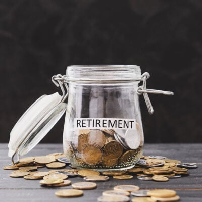 A clear jar labeled "retirement," surrounded by coins