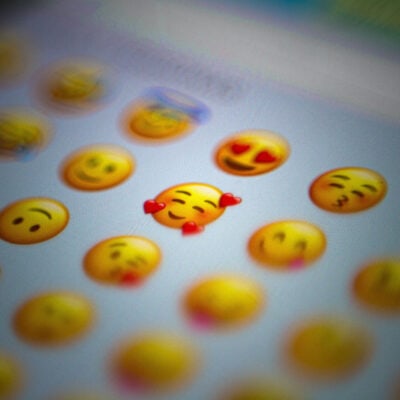 a selection of emojis from a screen; the majority of them are blurred out except for the smiling yellow face with 3 hearts