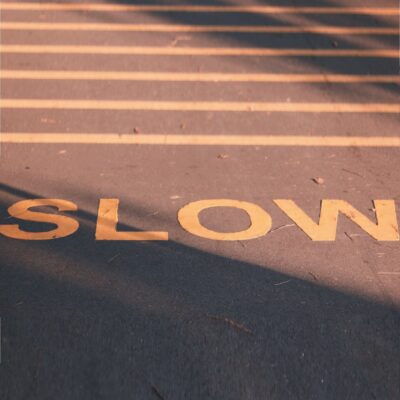 marking on road reads SLOW; there are yellow lines above it