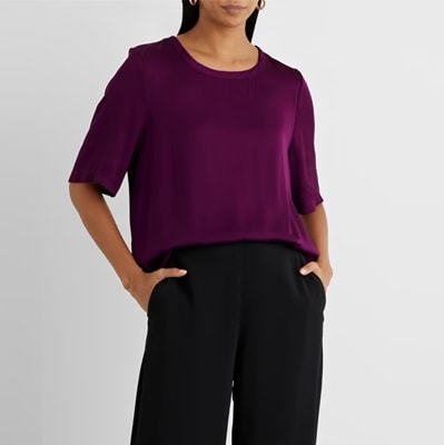A woman wearing a purple top and black pants
