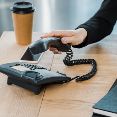 cropped photo of businesswoman picking up phone handset