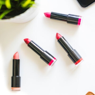 three lipsticks splayed on a white table; you can vaguely see a plant in the upper left-hand corner of the overhead shot
