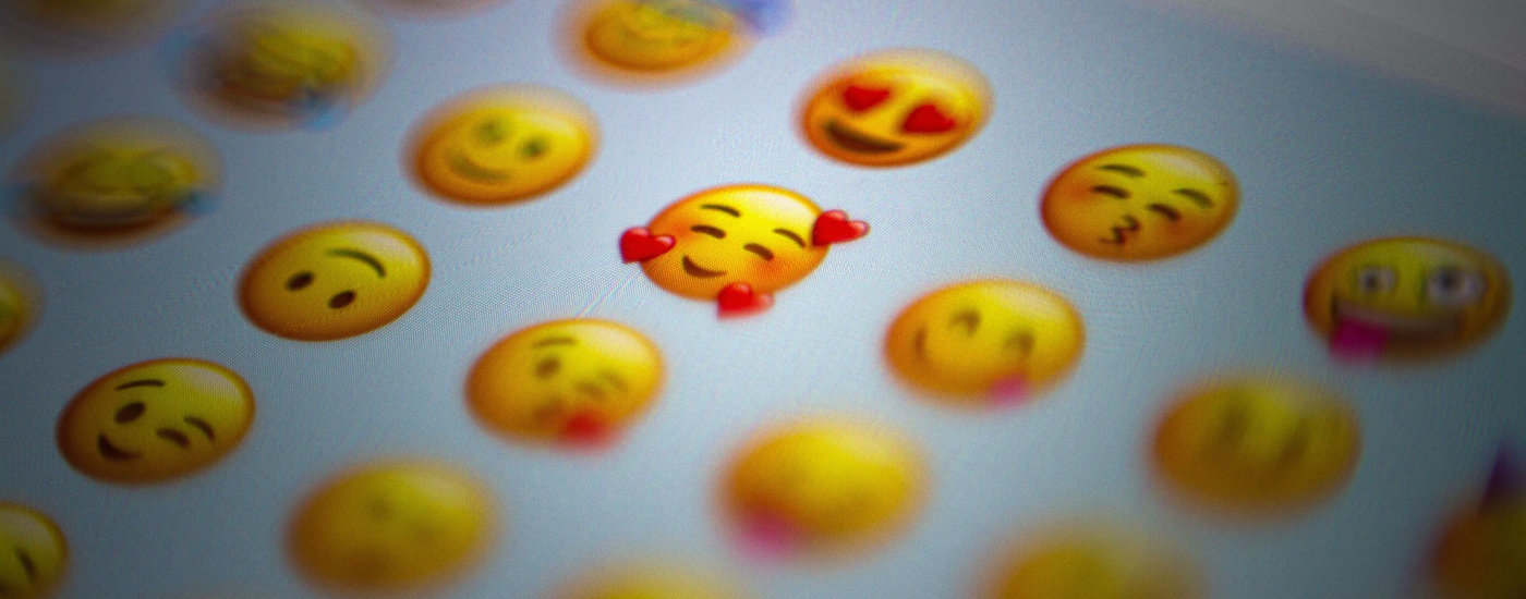 a selection of emojis from a screen; the majority of them are blurred out except for the smiling yellow face with 3 hearts