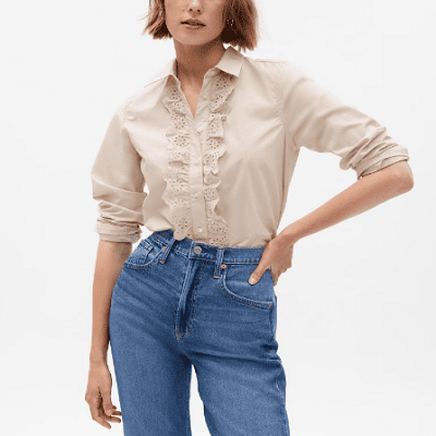 A woman wearing a cream-colored blouse and denim pants